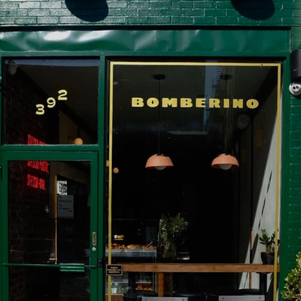 The green exterior of Bomberino cafe, with its name in gold letters on the window.