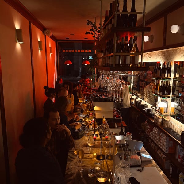 Patrons enjoying drinks and food at the Bomberino cafe bar, illuminated by warm, red lighting.